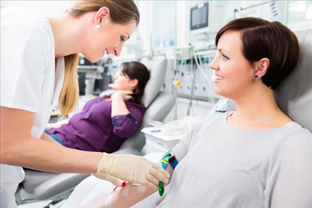 Phlebotomist smiling at patient trying to extract blood