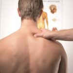 A kinesiologist examining a man's back